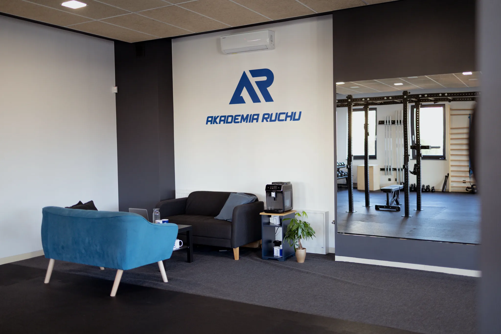 Strefa wypoczynkowa studia z niebieską kanapą i logo Akademii Ruchu
